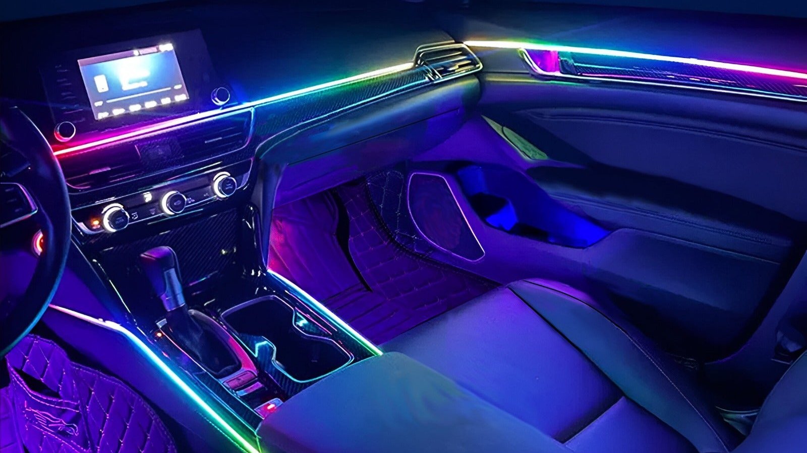 Car interior at night lit with rainbow ambient LED strips on the dashboard, doors, console, and footwells