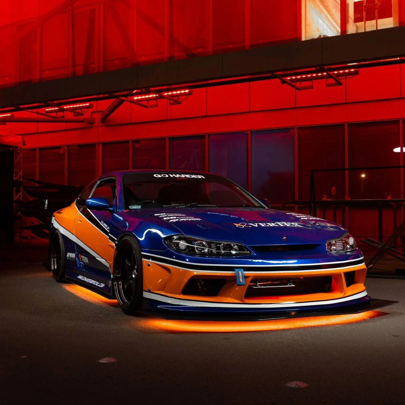 Orange and blue car with glowing undercarriage in a dark setting