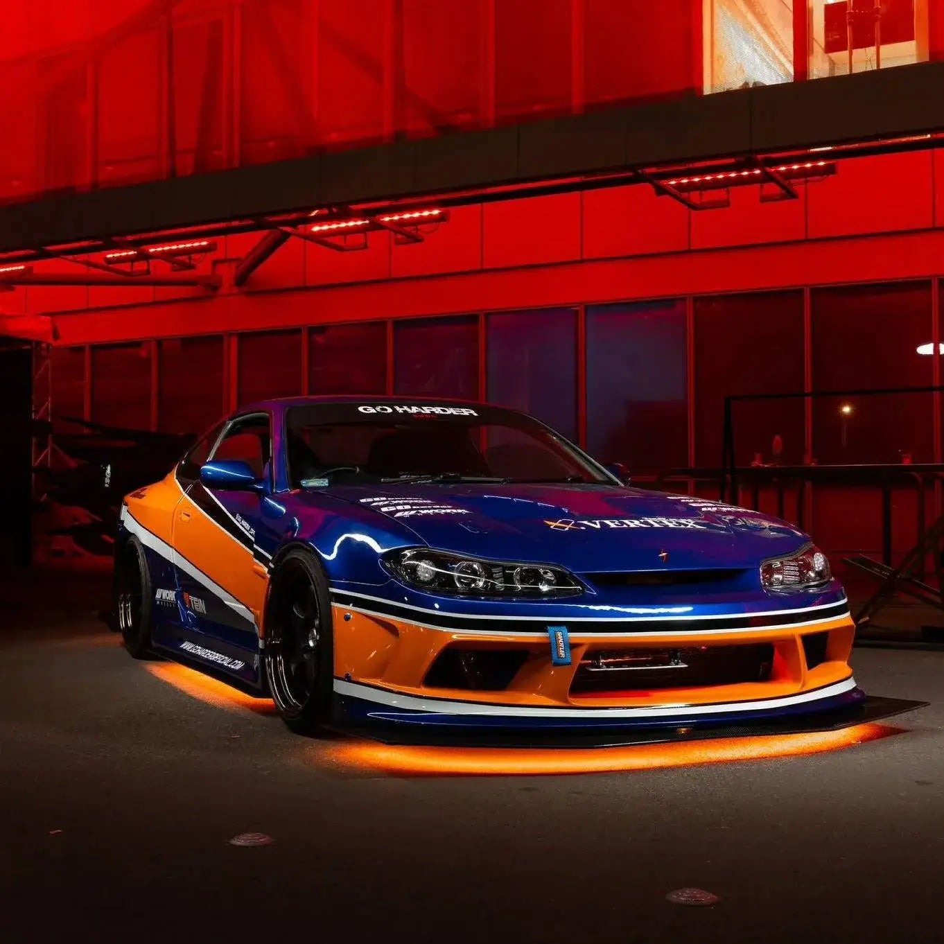 Orange and blue car with glowing undercarriage in a dark setting