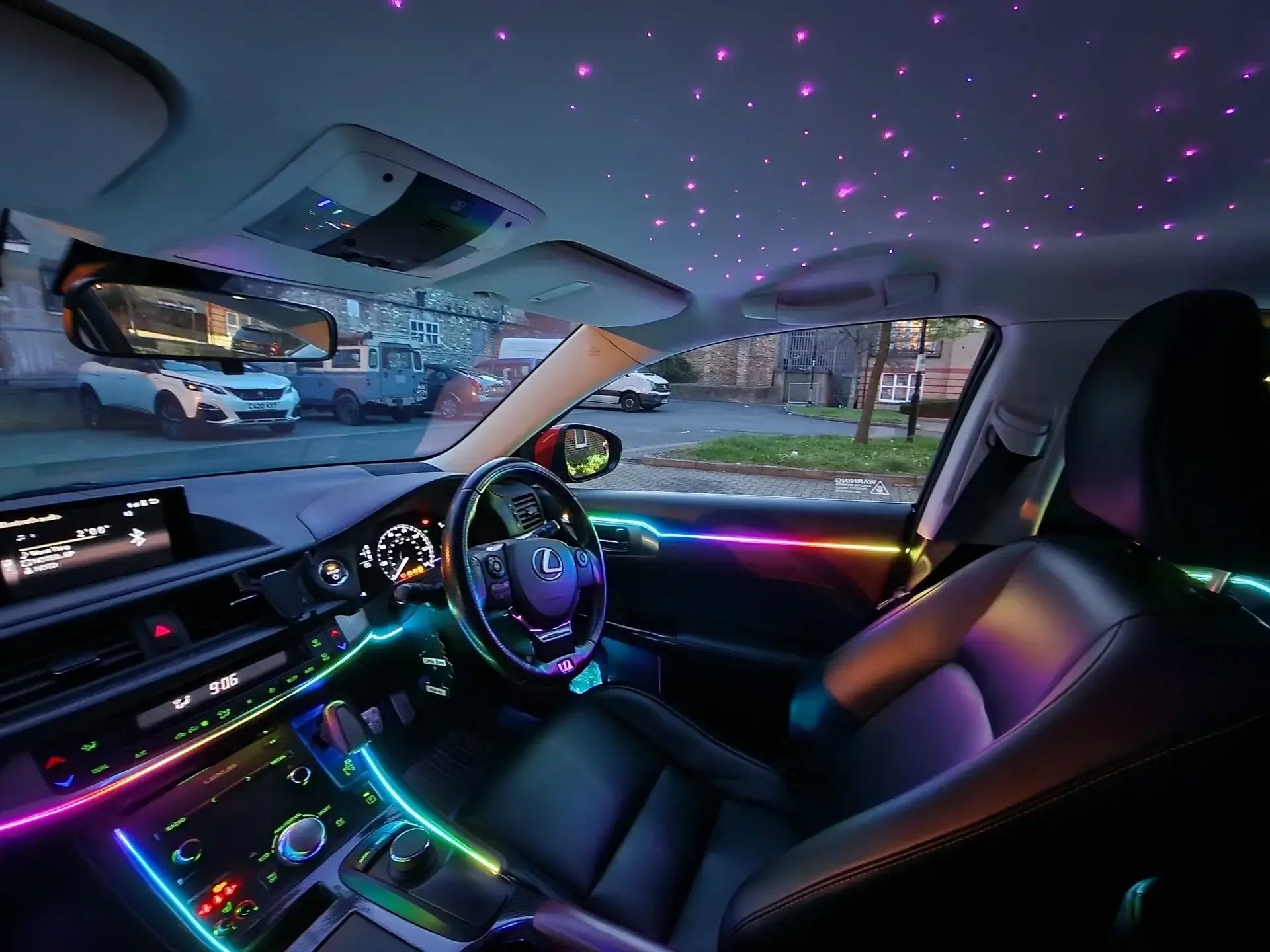 Custom Lexus CT200h interior featuring galaxy bundle with purple starlight headliner and rainbow RGB ambient lighting strips along the center console and dashboard