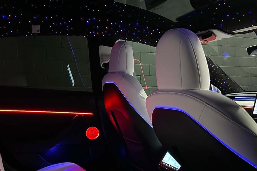 "Galaxy bundle custom interior lighting kit installed in Tesla Model 3 or Model Y with white interior, featuring blue starlight headliner and red ambient door strips
