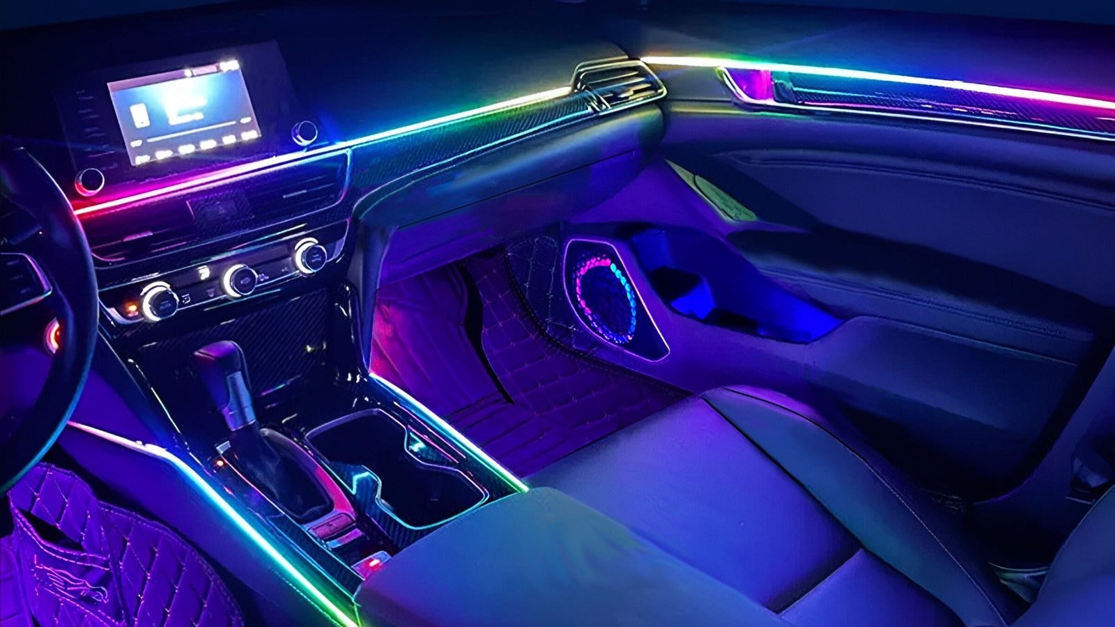 Full cabin ambient lighting result with rainbow LED strips and illuminated speaker rings in a car interior at night