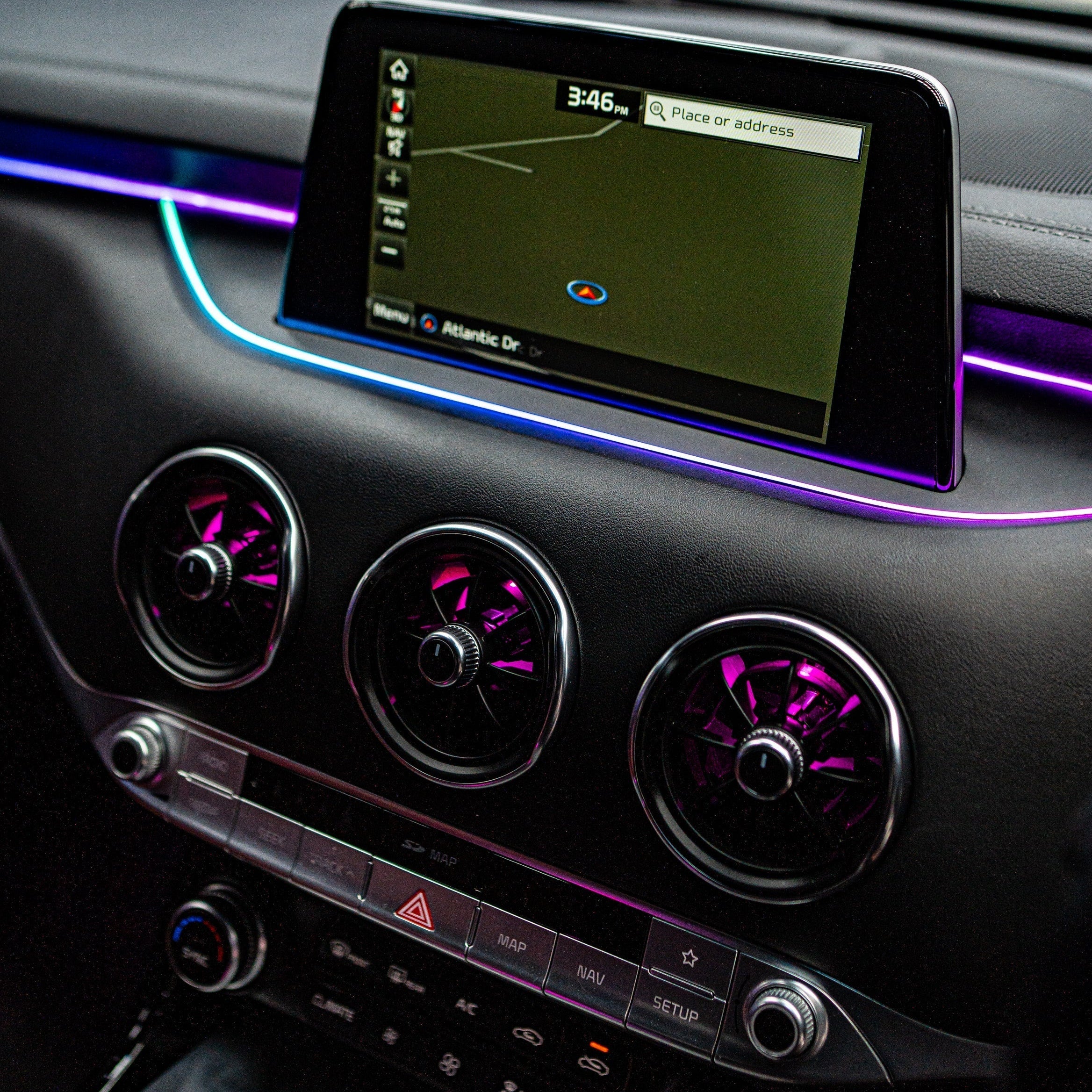 Car dashboard with air vents and a navigation screen, illuminated by purple LED lights, Ambient lighting DIY