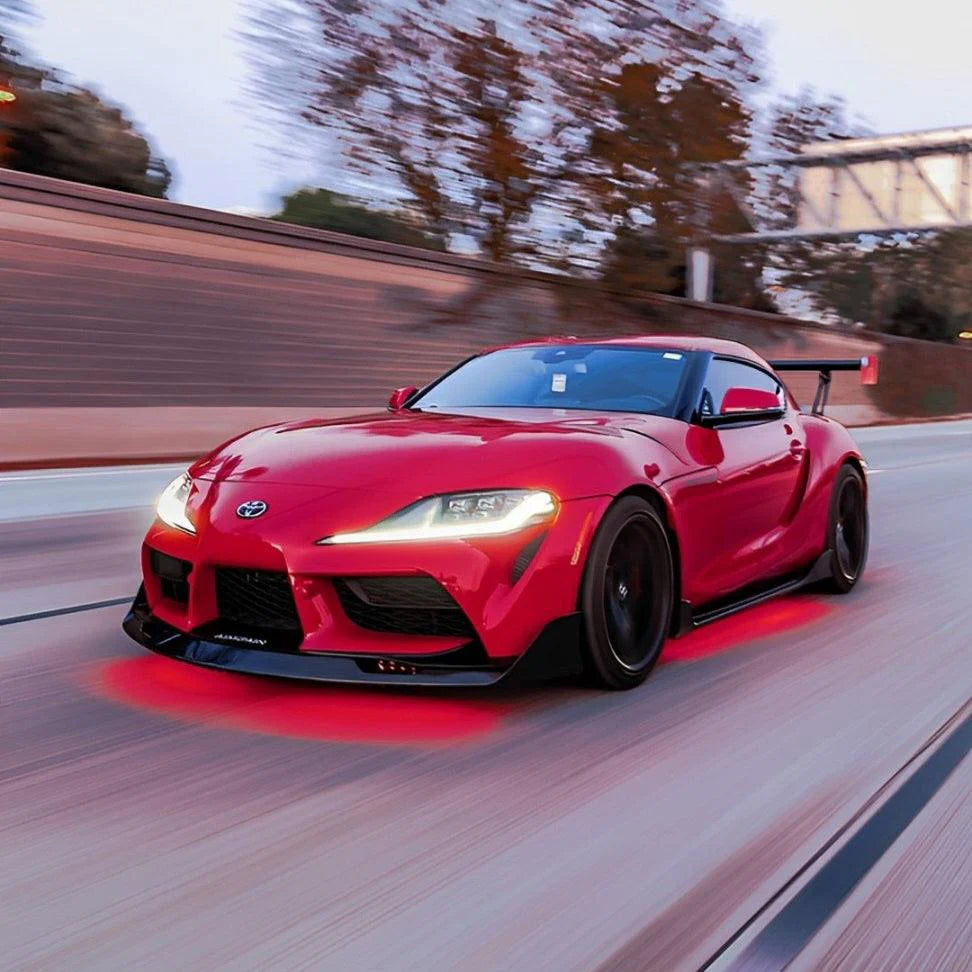 Red sports car driving on a road with blurred background and underbody underglow lighting RGB