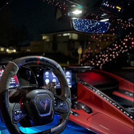 Luxury vehicle interior Corvette with steering wheel and dashboard at night.