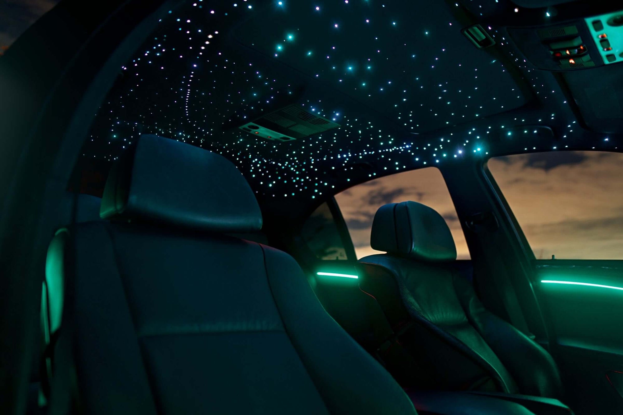 Galaxy bundle custom car interior lighting kit installed in BMW interior, featuring teal cyan starlight headliner around sunroof and matching ambient door strips