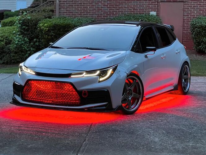 White car with red lights on a driveway. under-body RGB lights/underglow fast and furious lights 