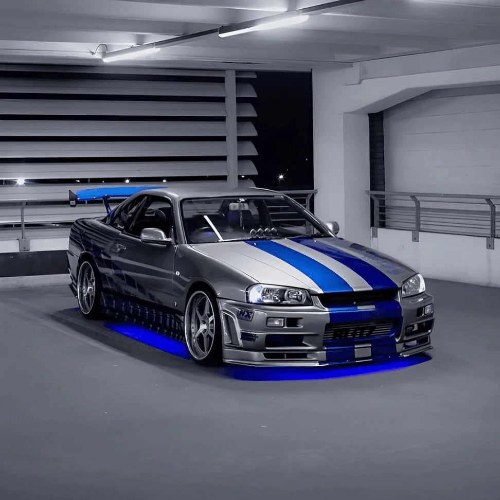 Silver sports car with blue stripes in a garage with Underbody ambient lighting, underglow underbody lights. 
